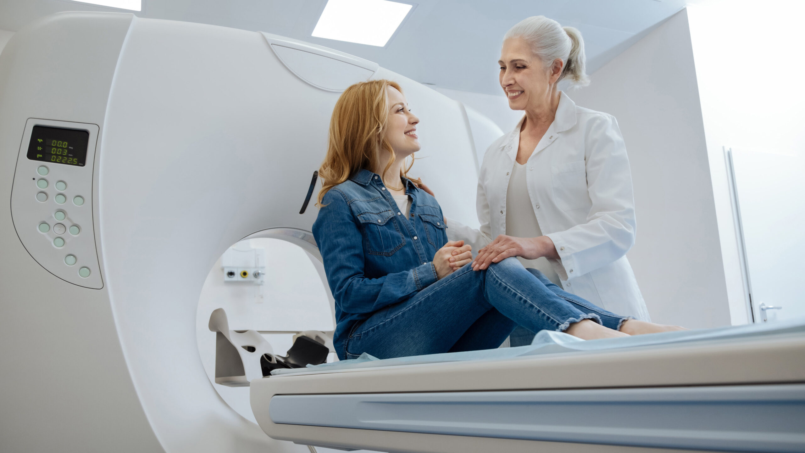Kobieta rozmawiająca z lekarką przy urządzeniu do mammografii
