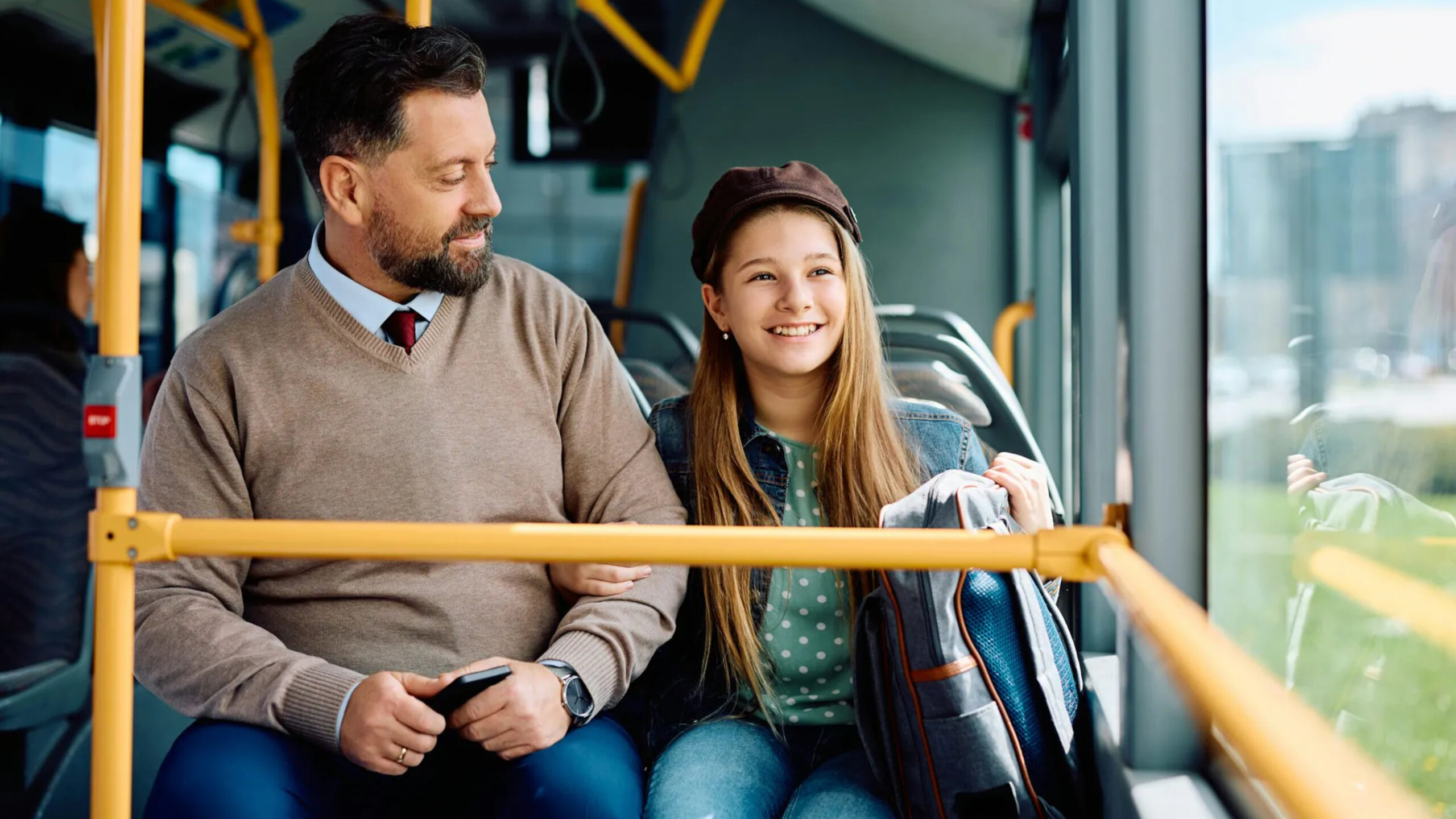 Transport publiczny Mężczyzna i uśmiechnięta nastolatka siedzą w nowoczesnym autobusie.