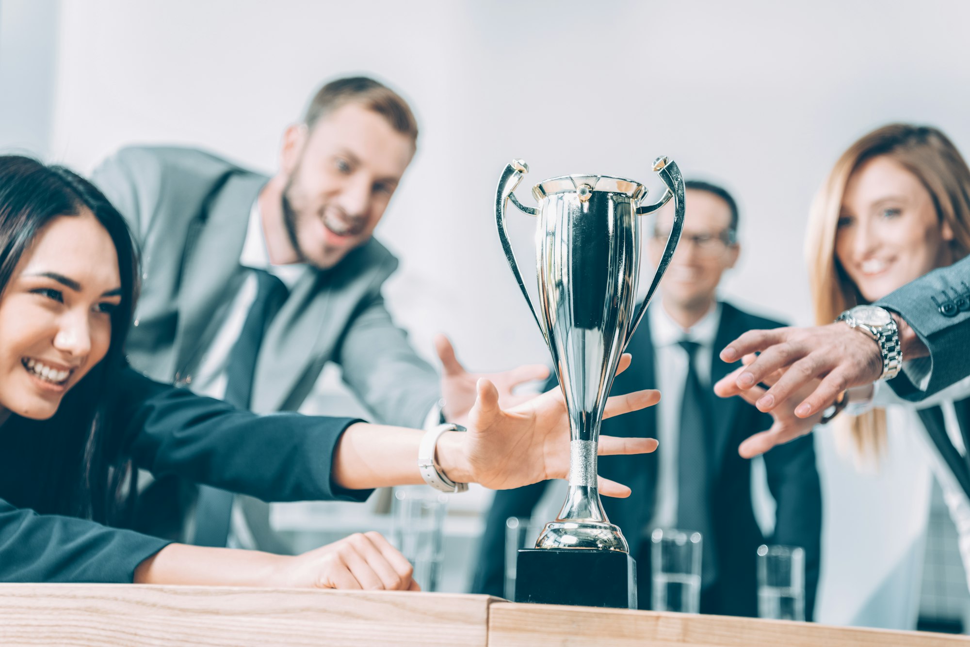 close-up shot of multiracial businesspeople trying to catch champion cup