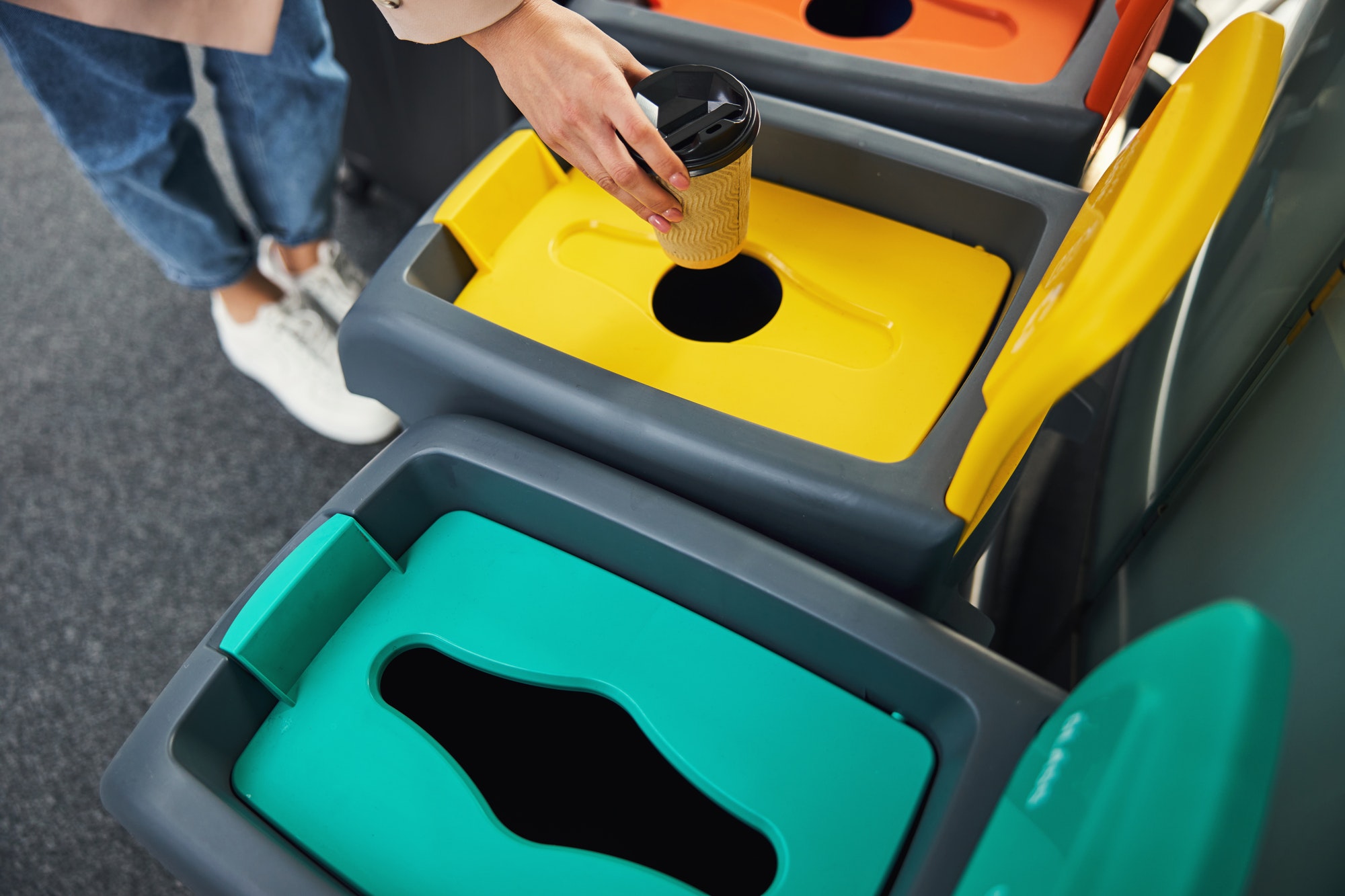 Female hand throwing coffee cup in trash can