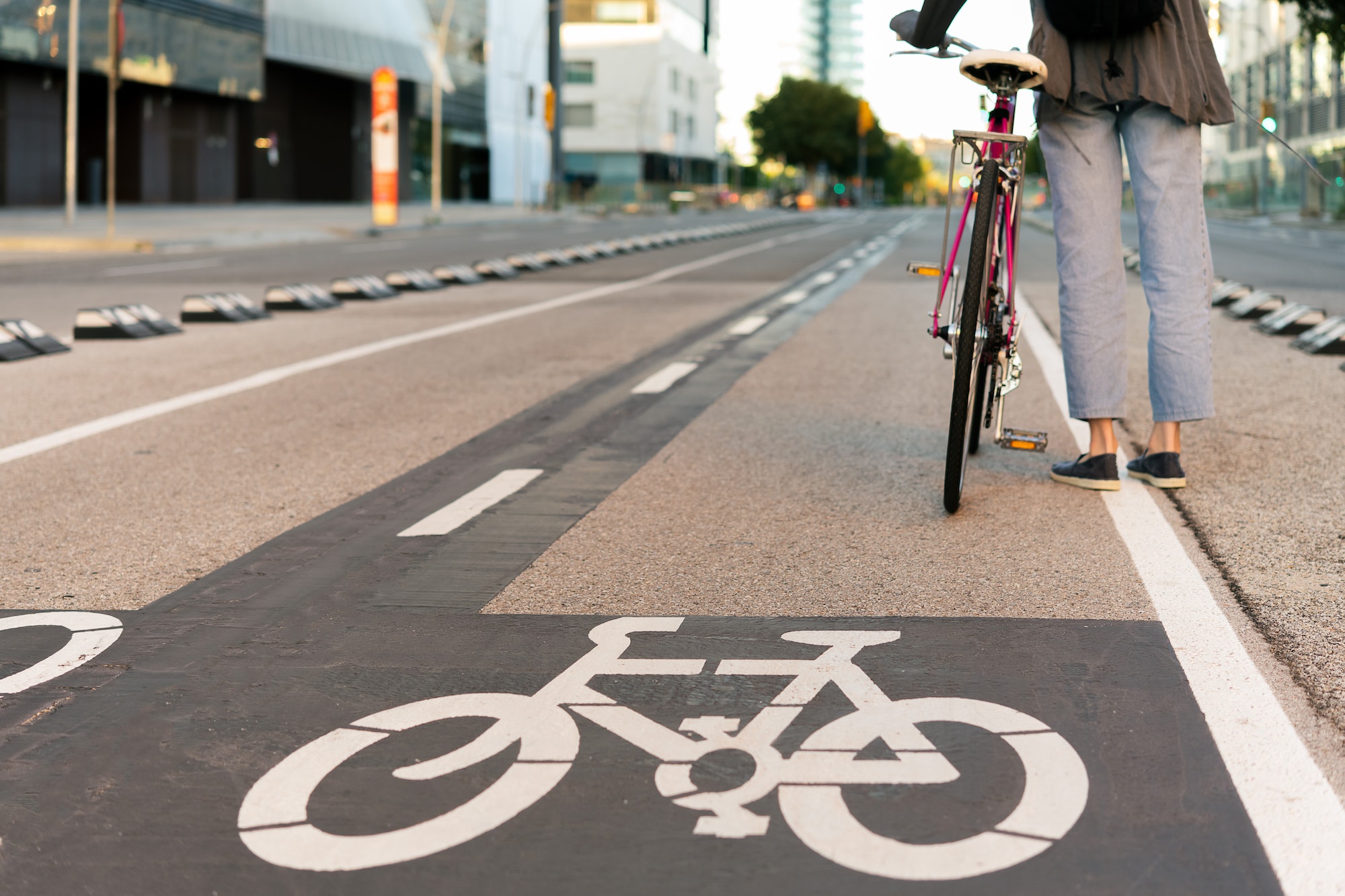 legs of young woman with bicycle by the bike path